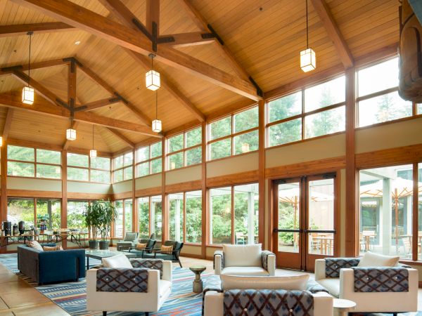 A spacious lounge with large windows, wooden beams, and modern furniture, creating a bright and welcoming ambiance.