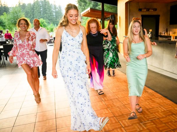 A group of people is dancing on a wooden floor, enjoying themselves in a lively setting with trees in the background.