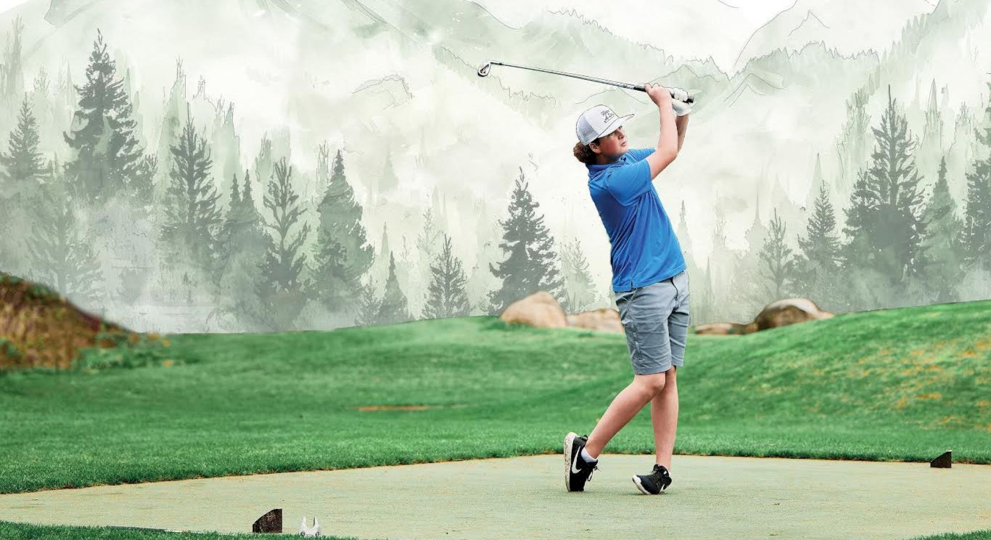 A person is playing golf on a course with a forest and mountain backdrop.